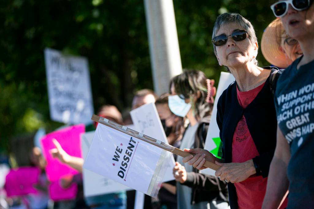 A woman holding a sign stands shoulder-to-shoulder with others during a protest against the Supreme Courts decision to overturn Roe v. Wade on Friday along Broadway in Everett, Washington. (Ryan Berry / The Herald)