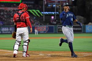 Seattle Mariners' Julio Rodriguez, right, celebrates after he scored on a single by Kevin Padlo as Los Angeles Angels catcher Kurt Suzuki stands at the plate during the sixth inning of a baseball game Saturday, June 25, 2022, in Anaheim, Calif. (AP Photo/Mark J. Terrill)