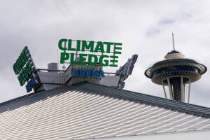 The roof-top sign for Climate Pledge Arena is shown next to the Space Needle, Wednesday, Oct. 20, 2021, ahead of the NHL hockey Seattle Kraken's home opener Saturday against the Vancouver Canucks in Seattle. The historic angled roof of the former KeyArena was preserved, but everything else inside the venue, which will also host concerts and be the home of the WNBA Seattle Storm basketball team, is brand new. (AP Photo/Ted S. Warren)