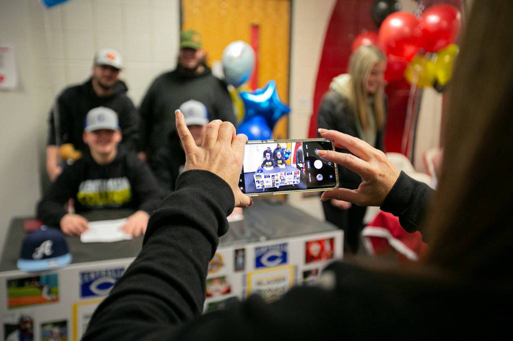 Mikealyn Rogers takes a photo of her son, Brayden Rogers, and fellow baseball player Issiah Holeman during National Signing Day Wednesday, Feb. 2, 2022, at Marysville Pilchuck High School in Marysville, Washington. (Ryan Berry / The Herald)