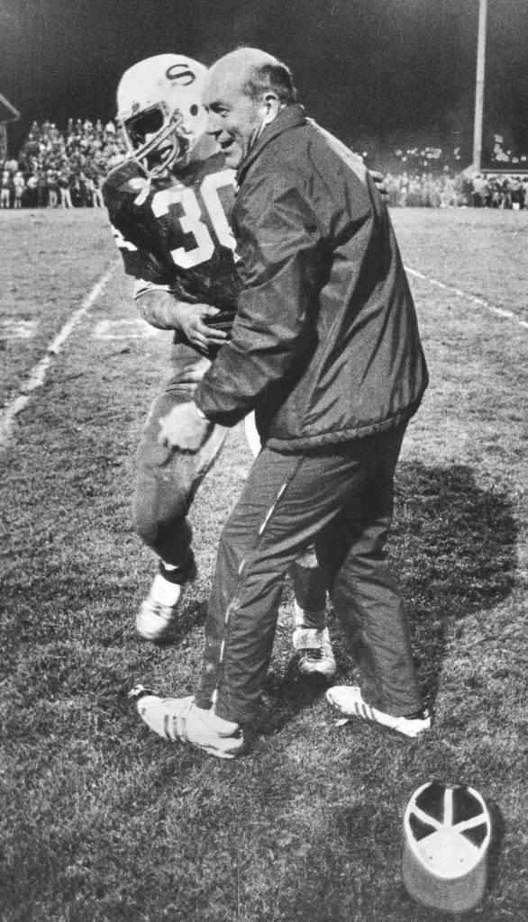 Rick Fenney is given a congratulatory hug by Snohomish High School football coaching legend Dick Armstrong after he scores his fifth touchdown. (Gary Voth / The Herald)