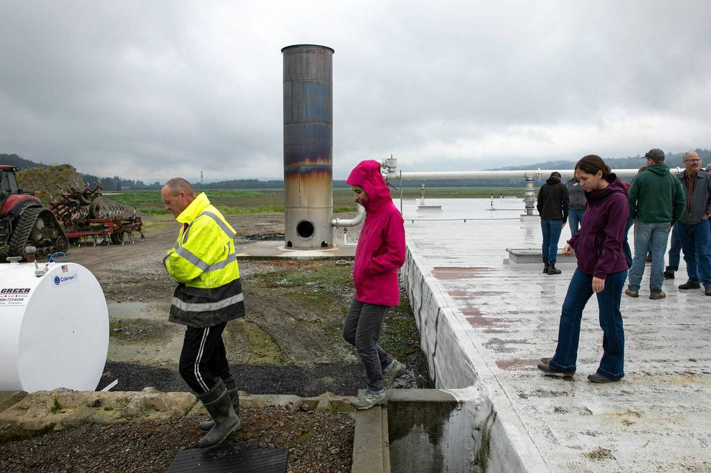 People walk off of the top of the anaerobic digester at Werkhoven Dairy while touring the facility on June 17 in Monroe. (Ryan Berry / The Herald)