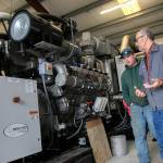 Jon Van Nieuwenhuyzen walks with a person past the new generator as it is being installed on June 17 in Monroe. (Ryan Berry / The Herald)