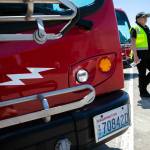 An Everett Transit employee walks between two electric buses, which are marked with a lightning bolt decal, on June 27 at the Everett Transit facility. (Ryan Berry / The Herald)