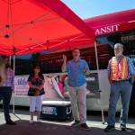 Everett Transit leaders discuss the new BattGenie system June 27 at the Everett Transit bus yard. The system uses old bus batteries as a backup power source. (Ryan Berry / The Herald)