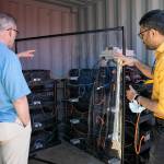 Everett Transit director Tom Hingson, left, asks BattGenie co-founder Chintan Pathak about the thousands of battery cells stored inside a container at the Everett Transit bus yard June 27. (Ryan Berry / The Herald)