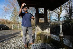 Alderwood Water & Wastewater District water quality tech assistant Matt Williams looks at the clarity of a water sample taken from the artesian well located along164th Street on Monday, April 2, 2018 in Lynnwood, Wa. The well," also known as Well No. 5 or the 164th Street Artesian Well is in excess of 400 feet in depth and flows at a rate of about 10 gallons per minute. (Andy Bronson / The Herald)