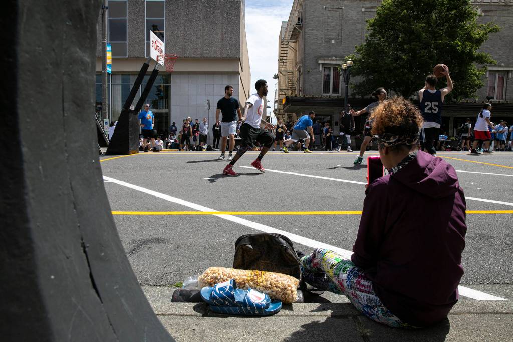 A woman films a game during Everett 3on3 Saturday, July 9, 2022, in downtown Everett, Washington. (Ryan Berry / The Herald)