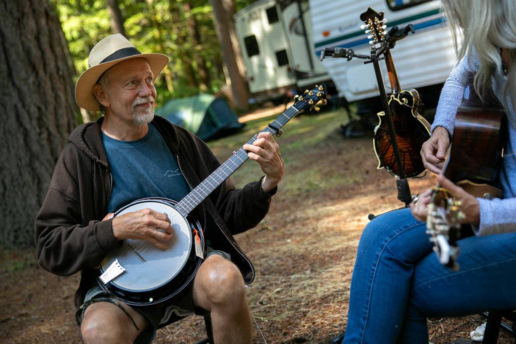 Tom Nechville and Linda Leavitt jam together in the shade on Wednesday, at Darrington Bluegrass Music Park in Darrington. Nechville and Leavitt, both now living in Oregon, are visiting the festival for the first time this year. (Ryan Berry / The Herald)