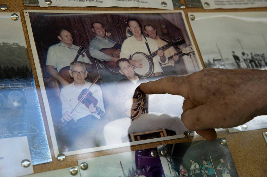 Patrick Robison, a former board member and promoter for the festival, points out different locals on a board full of old photos on Wednesday, at Darrington Bluegrass Music Park in Darrington. (Ryan Berry / The Herald)