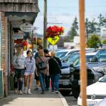 Two groups of pedestrians sneak past each other on a narrow sidewalk along 271st Street on Friday, in the Historic East Downtown in Stanwood. (Ryan Berry / The Herald)