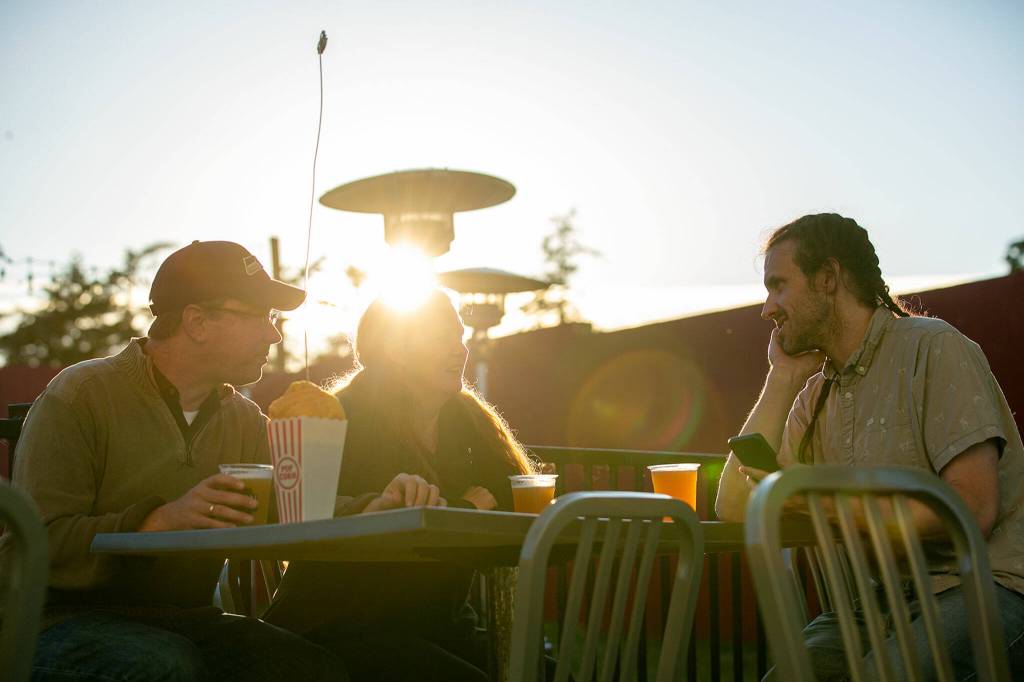 Ethan, Jessica and Reade McCardell sip on some beers at the Backlot Tavern at the Blue Fox Drive-In Theater. The tavern was added in 2020. (Ryan Berry / The Herald)