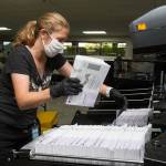 Catherine Berwicks loads ballots into a tray after scanning them at the Snohomish County Elections Ballot Processing Center onAug. 4, 2020 in Everett. (Andy Bronson / The Herald file photo)