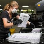 Catherine Berwicks loads ballots into a tray after scanning them at the Snohomish County Elections Ballot Processing Center on Tuesday, Aug. 4, 2020 in Everett, Wa.  (Andy Bronson / The Herald)