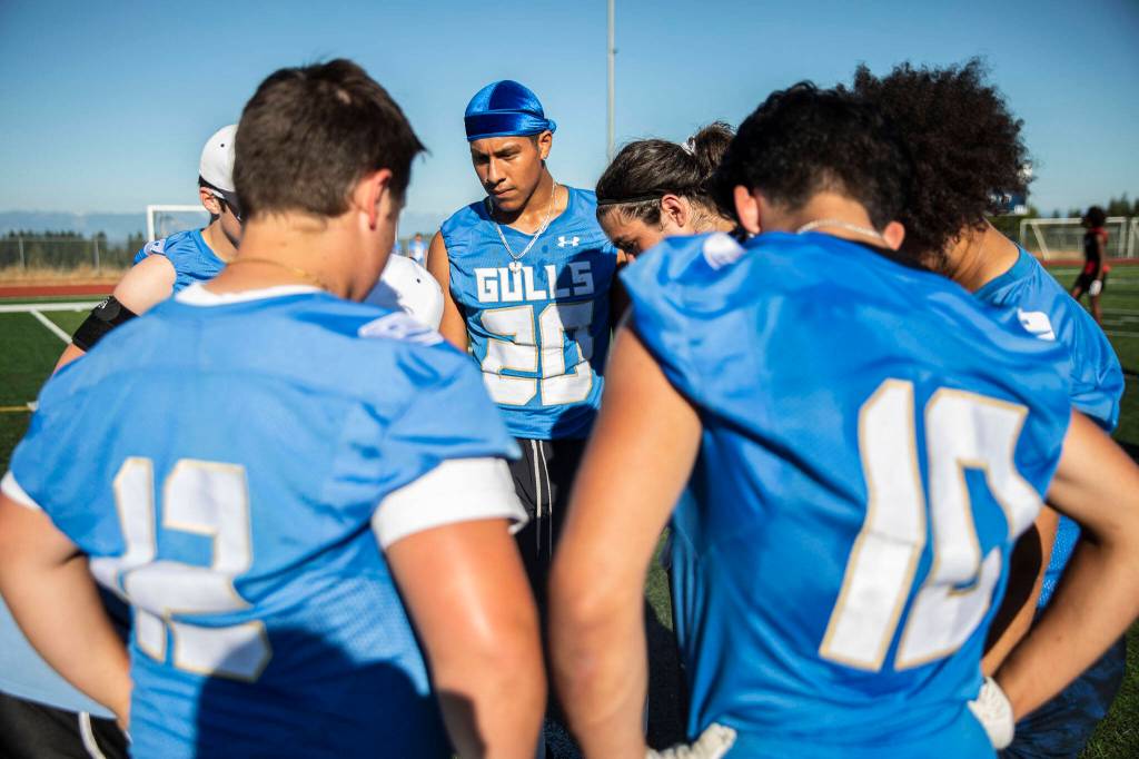 Everett players listen to their coach in a huddle during a 7on7 game at Glacier Peak High School on Wednesday, July 20, 2022 in Snohomish, Washington. (Olivia Vanni / The Herald)