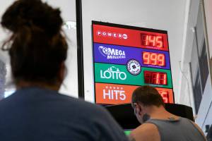 People wait in line to buy Mega Millions tickets as the sign above the lotto machine reads “999 Estimated Million” despite the payout now being over $1 billion on  Wednesday, July 27, 2022, at Safeway on Evergreen in Everett, Washington. (Ryan Berry / The Herald)