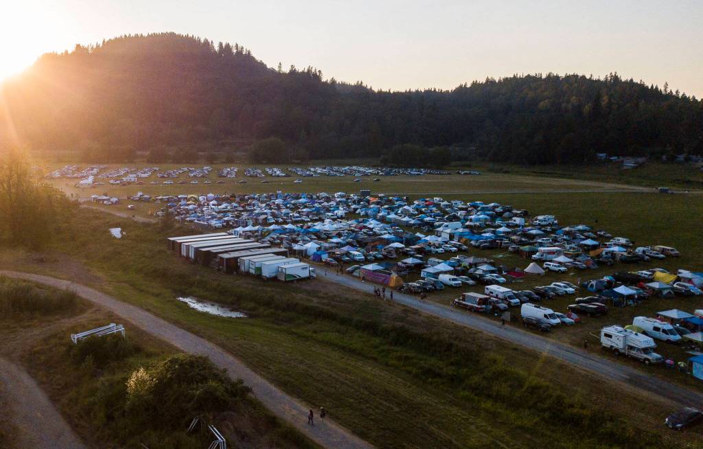 People walk along the paths past car camping as the sun sets at Summer Meltdown on Thursday, July 28, 2022 in Snohomish, Washington. (Olivia Vanni / The Herald)