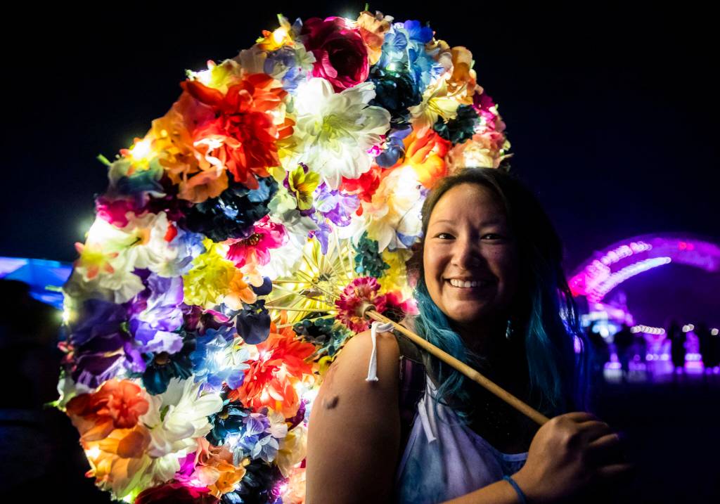 An attendee carries a flower and light covered umbrella at Summer Meltdown on Thursday, July 28, 2022 in Snohomish, Washington. (Olivia Vanni / The Herald)