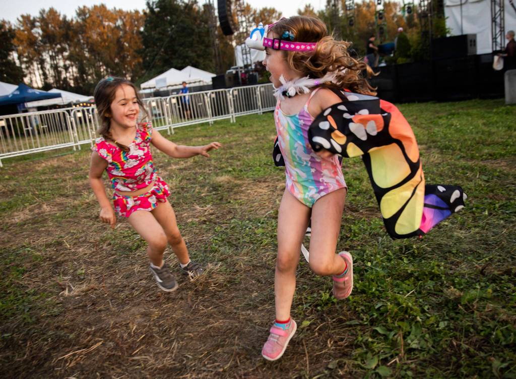 Coral Roussell, 4, left, chases Penelope Witter, 5, around the grass in front of the Garden Stage on Thursday, in Snohomish. (Olivia Vanni / The Herald)