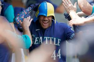 Seattle Mariners' Julio Rodriguez wears a helmet as he is greeted in the dugout after his three-run home run against the Texas Rangers during the seventh inning of a baseball game Wednesday, July 27, 2022, in Seattle. (AP Photo/Ted S. Warren)