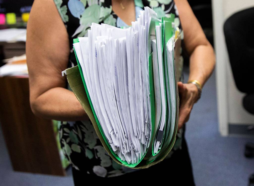 Van Kuno carries a large folder of Ukrainian refugee rental applications and other expenses on July 20, in Everett. (Olivia Vanni / The Herald)