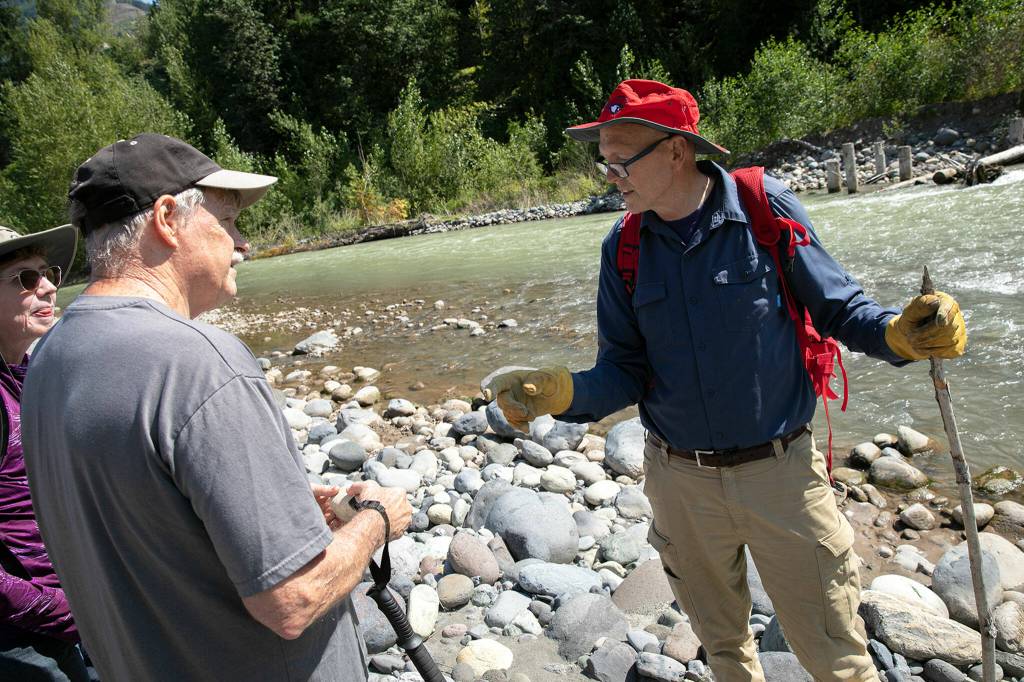 Jon Elmgren, president of the Everett Rock and Gem Club, talks with two club members while out searching for olivine and other minerals on July 23 along the Nooksack River near Deming. (Ryan Berry / The Herald)