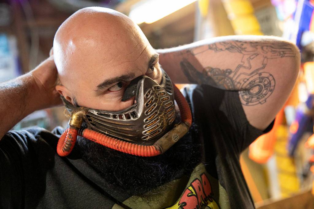 Josh Haazard puts on a mask he created at the beginning of the COVID-19 pandemic. (Ryan Berry / The Herald)