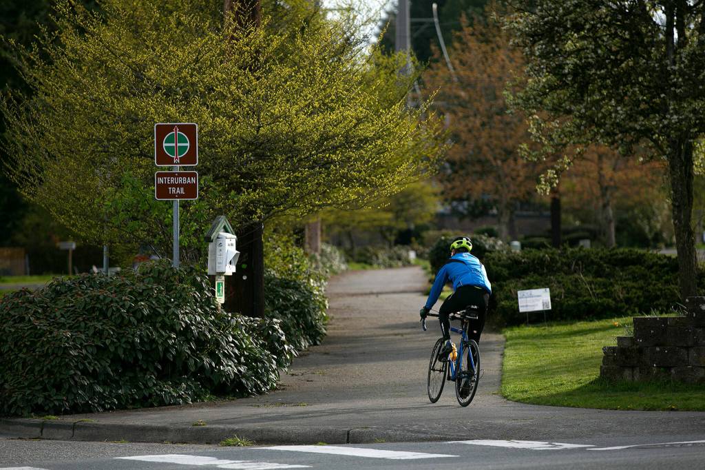 A cyclist crosses Madison Street along the Interurban Trail on April 14, in Everett. The City of Everett is considering adding bike lanes to Madison Street to connect the Interurban Trail to other bike routes in the area. (Ryan Berry / The Herald)