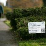 A pedestrian walks along the Interurban Trail and past a sign asking for public input on proposed bike lanes on Madison Street on April 14, in Everett. (Ryan Berry / The Herald)