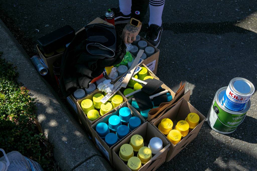 Faust, an artist from Arizona, grabs a new can of spray paint while working on a mural with some fellow artists Friday, in downtown Everett. (Ryan Berry / The Herald)