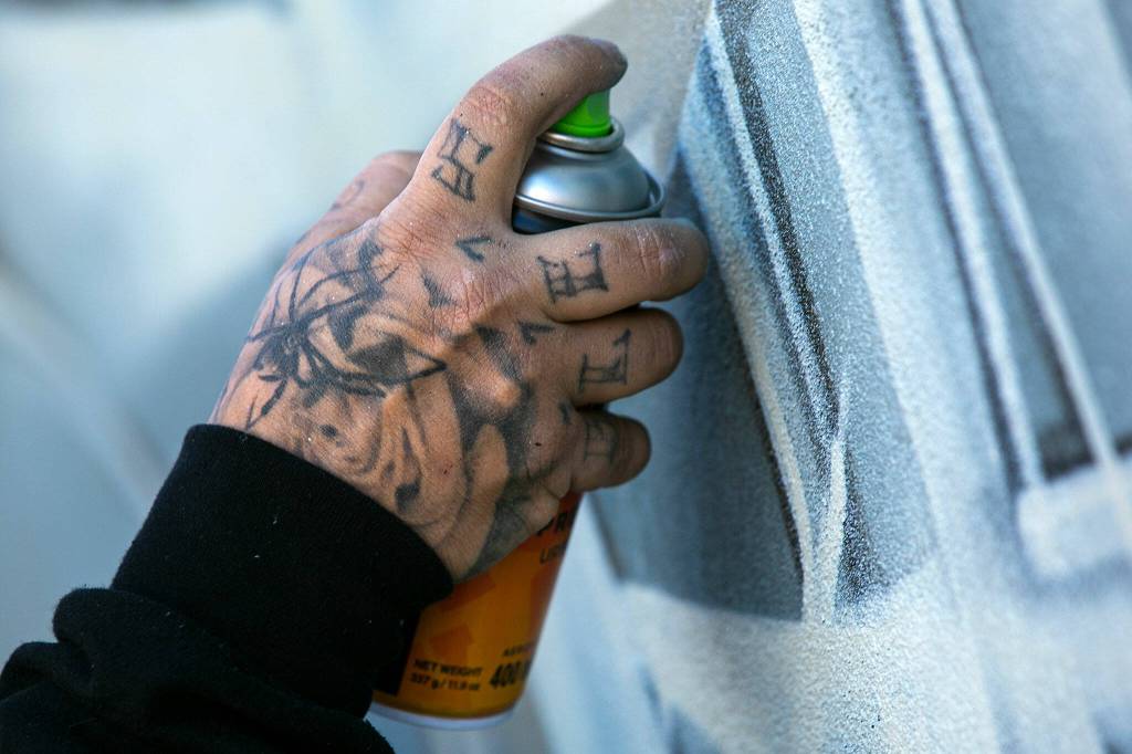 Faust lightly adds tone to the beginnings of a piece he and fellow artists are creating for Going All City NW on Friday, in downtown Everett. (Ryan Berry / The Herald)