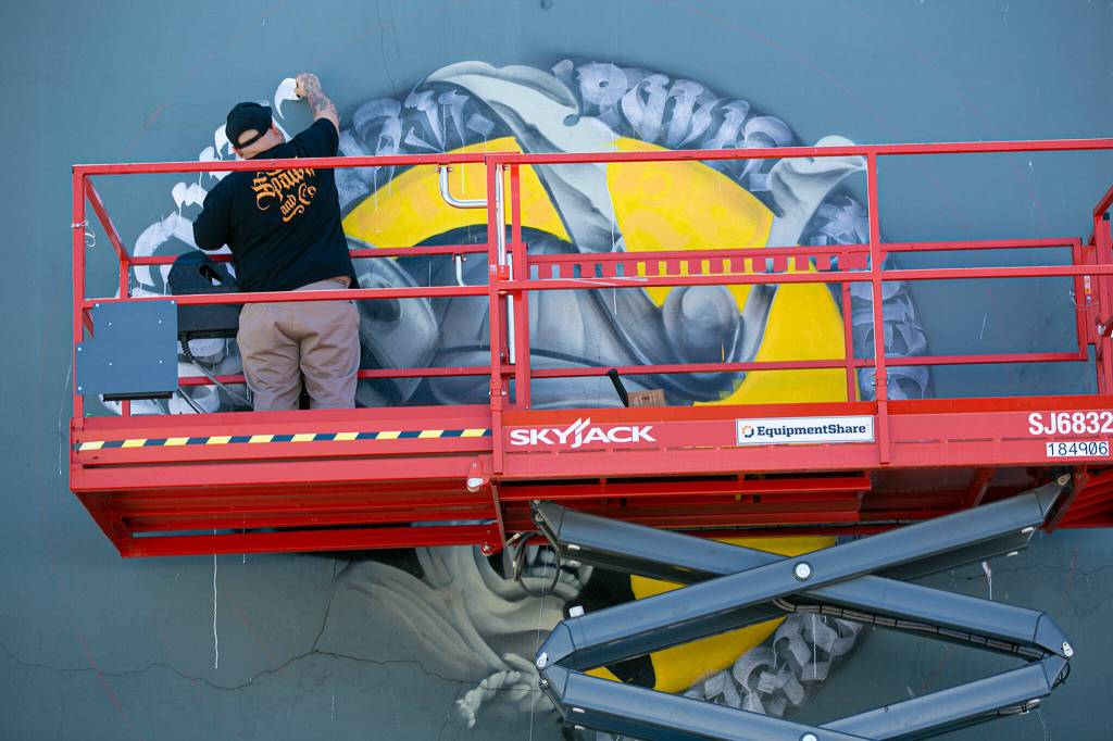 Spawk works on a new downtown from the top of a shaky scissor lift on Friday, along Rucker Ave. in Everett. (Ryan Berry / The Herald)