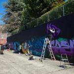 More than half a dozen artists come together to put their mark on an alley wall on Friday, in downtown Everett. Many passersby took a moment to swing through the alley and ask questions about Going All City NW. (Ryan Berry / The Herald)