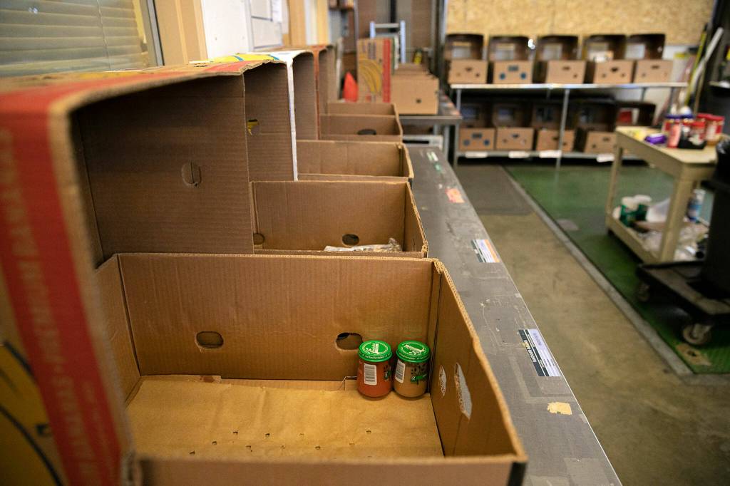A dry goods packing station is nearly devoid of food as donations plummet on Friday, Aug. 5, 2022, at the Everett Food Bank on Broadway in Everett, Washington. (Ryan Berry / The Herald)