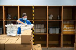 Carri Tokareff, an Everett Food Bank employee since late last year, packs bags while surrounded by empty shelves Friday, Aug. 5, 2022, at the Everett Food Bank on Broadway in Everett, Washington. Tokareff said the food bank has never seen a shortage of food like this one, and that it’s due to an economic climate in which more people are using the food bank’s services and fewer people are able to donate. The food bank has had to reduce its services from once a week per family to twice a month, and the boxes of supplies they do offer are now less diverse and missing things like sanitary products. (Ryan Berry / The Herald)