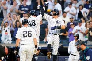 New York Yankees' DJ LeMahieu (26) looks on as Anthony Rizzo (48) celebrates with Aaron Judge after Rizzo hit a three-run home run during the first inning of a baseball game against the Seattle Mariners, Monday, Aug. 1, 2022, in New York. (AP Photo/Frank Franklin II)