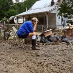 Teresa Reynolds sits exhausted as members of her community clean the debris from their flood ravaged homes at Ogden Hollar in Hindman, Ky., Saturday, July 30, 2022. (AP Photo/Timothy D. Easley)