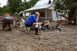 Teresa Reynolds sits exhausted as members of her community clean the debris from their flood ravaged homes at Ogden Hollar in Hindman, Ky., Saturday, July 30, 2022. (AP Photo/Timothy D. Easley)
