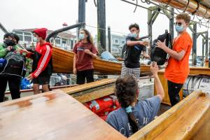 Members of Casino Connect line up to stow luggage Tuesday morning aboard the Adventuress in Everett on August 9, 2022.  The teens will go on a four-day sailing trip where they learn about maritime skills and environmental science. (Kevin Clark / The Herald)