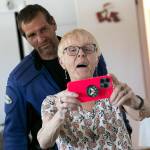 Rev. Barbara Rasberry, with her son, Mark Irwin, behind her, demonstrates how to properly take a photo using her chapel backdrop. (Ryan Berry / The Herald)