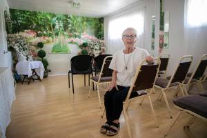 Rev. Barbara Raspberry, dressed in her go-to officiating garments, sits in the indoor chapel at her home, the Purple Wedding Chapel, on Tuesday, Aug. 9, 2022, in Everett, Washington. The space used to be two bedrooms, but she and her husband Don took down a wall converted them into a room for wedding ceremonies the day after their youngest son moved out over 20 years ago. The room can seat about 20 for in-person ceremonies, plus it serves as a changing room for brides and is the setting for virtual weddings that Raspberry officiates between brides and their incarcerated fiancees at the Monroe Correctional Complex. (Ryan Berry / The Herald)