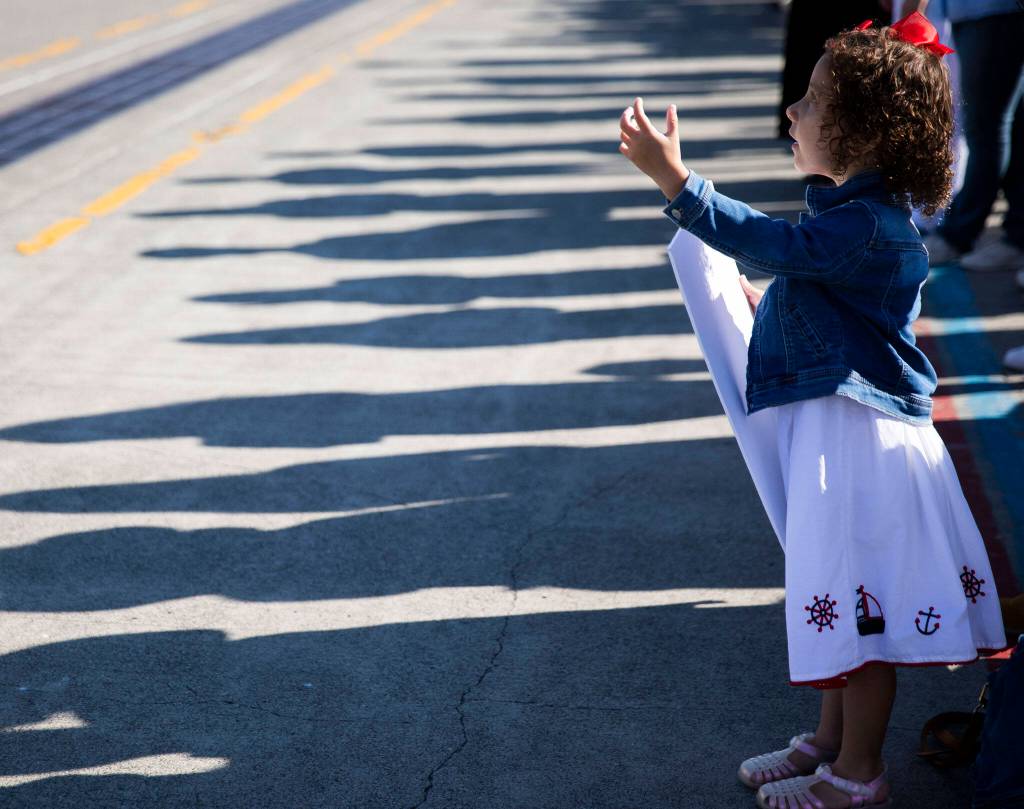 A young girl looks up and waves at her dad on the U.S.S. Gridley at Naval Station Everett on Thursday, in Everett. (Olivia Vanni / The Herald)