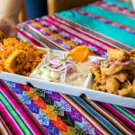 Co-owner of Rinconcito Peruano Restaurant Genesis Rojas brings out a Triple Marino dish that consists of arroz con mariscos, ceviche and jalea mixta on Saturday, in Lynnwood. (Olivia Vanni / The Herald)