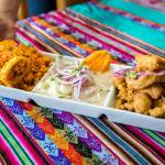 Co-owner of Rinconcito Peruano Restaurant Genesis Rojas brings out a Triple Marino dish that consists of arroz con mariscos, ceviche and jalea mixta on Saturday, Aug. 13, 2022 in Lynnwood, Washington. (Olivia Vanni / The Herald)