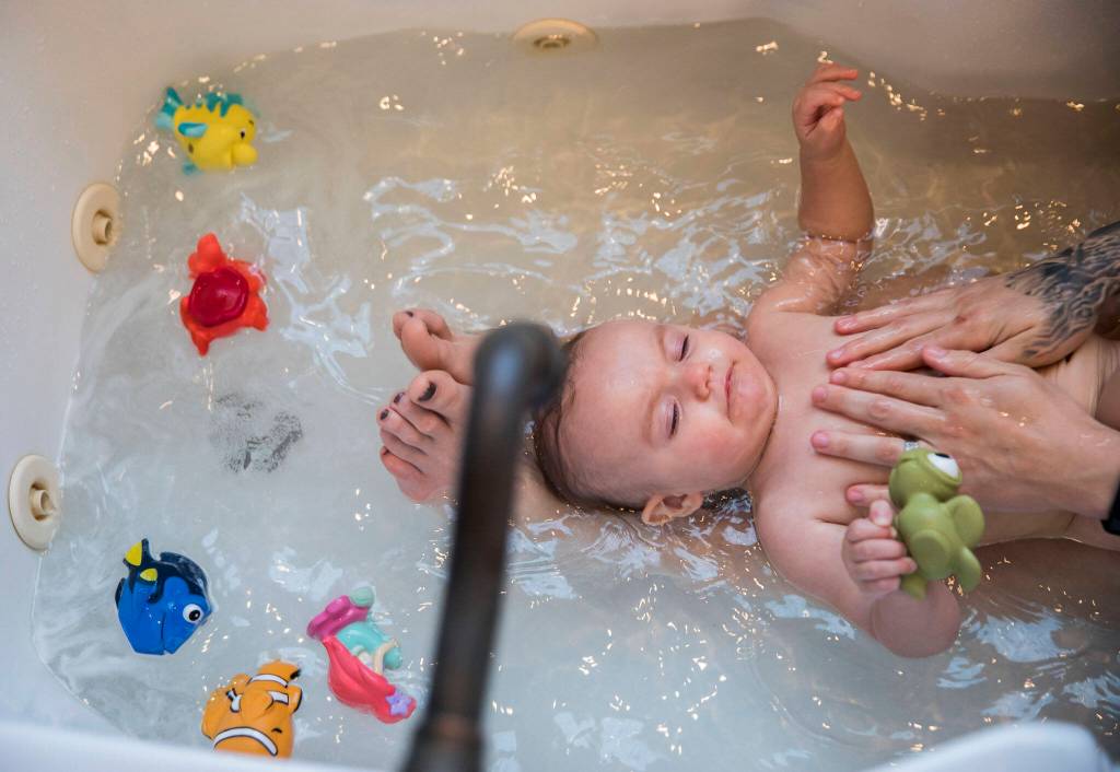 Austin holds onto her favorite bath toy, Squirt from Finding Nemo, while her mother Miranda Granger bathes her on Monday, May 16, 2022, in Lake Stevens, Washington. (Olivia Vanni / The Herald)