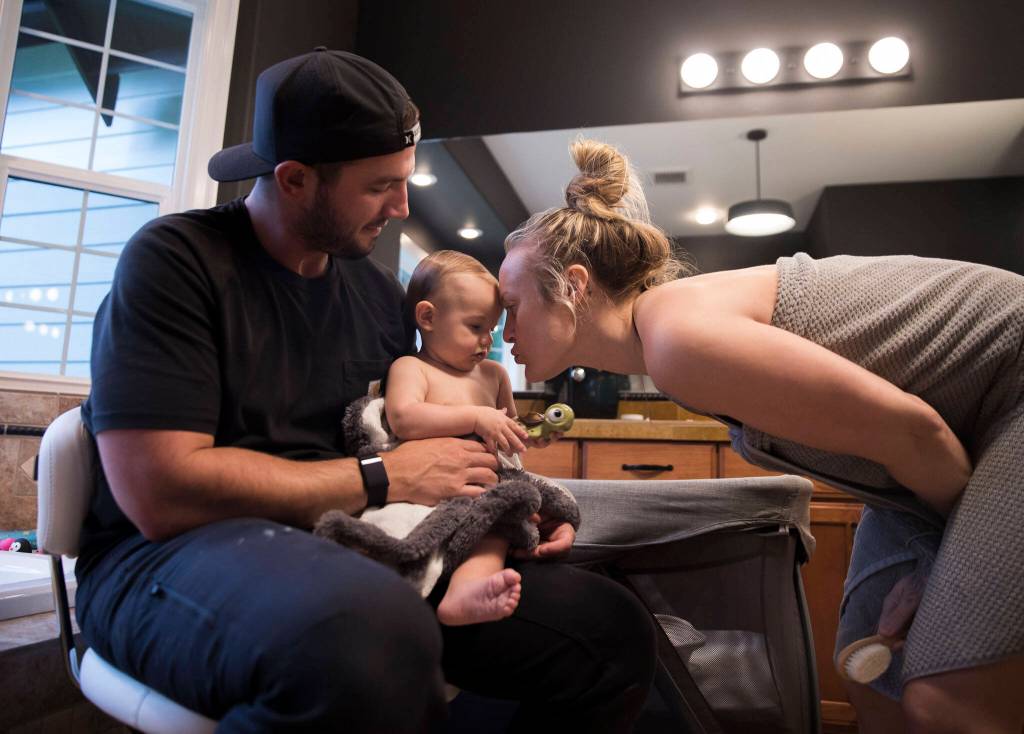 Kaden Barish holds his daughter Austin while her mother Miranda Granger bends down to kiss her after a bath on Monday, May 16, 2022, in Lake Stevens, Washington. (Olivia Vanni / The Herald)