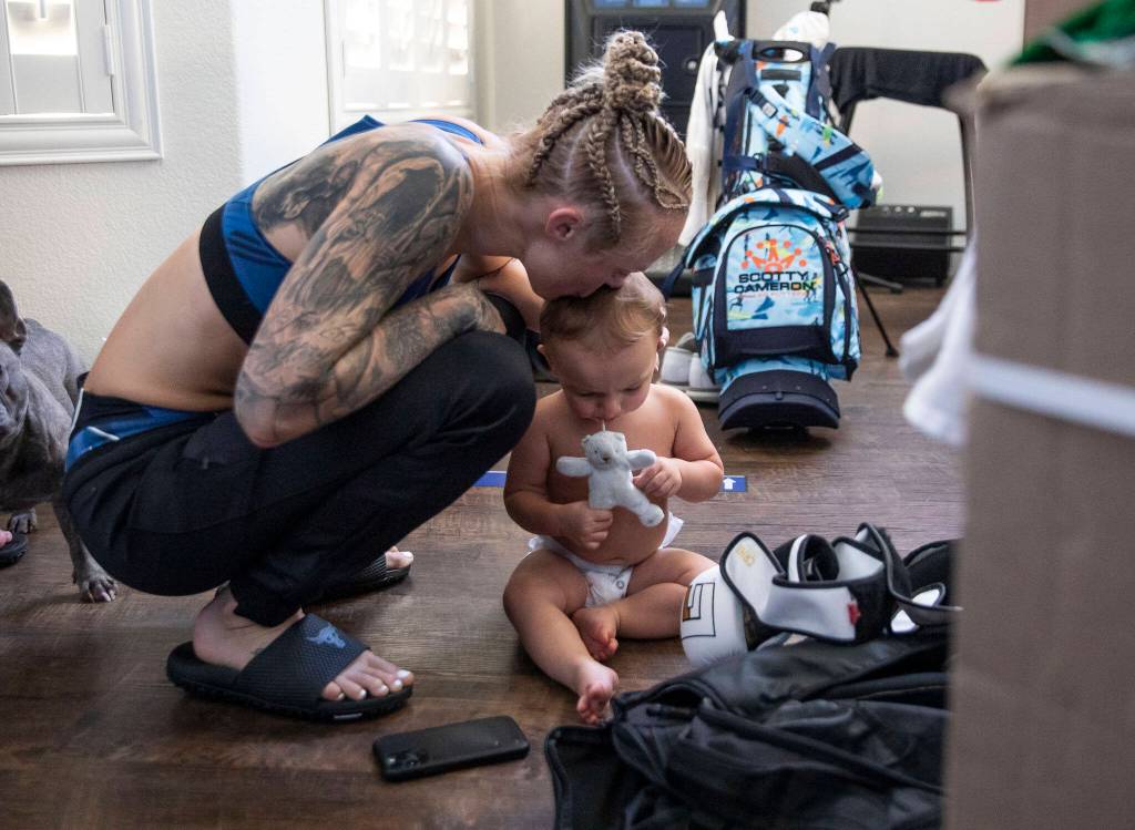 Miranda Granger squats and kisses Austin on the head with tears in her eyes after losing her fight against Cory McKenna at the UFC Apex on Aug. 6, 2022, in Las Vegas. (Olivia Vanni / The Herald)