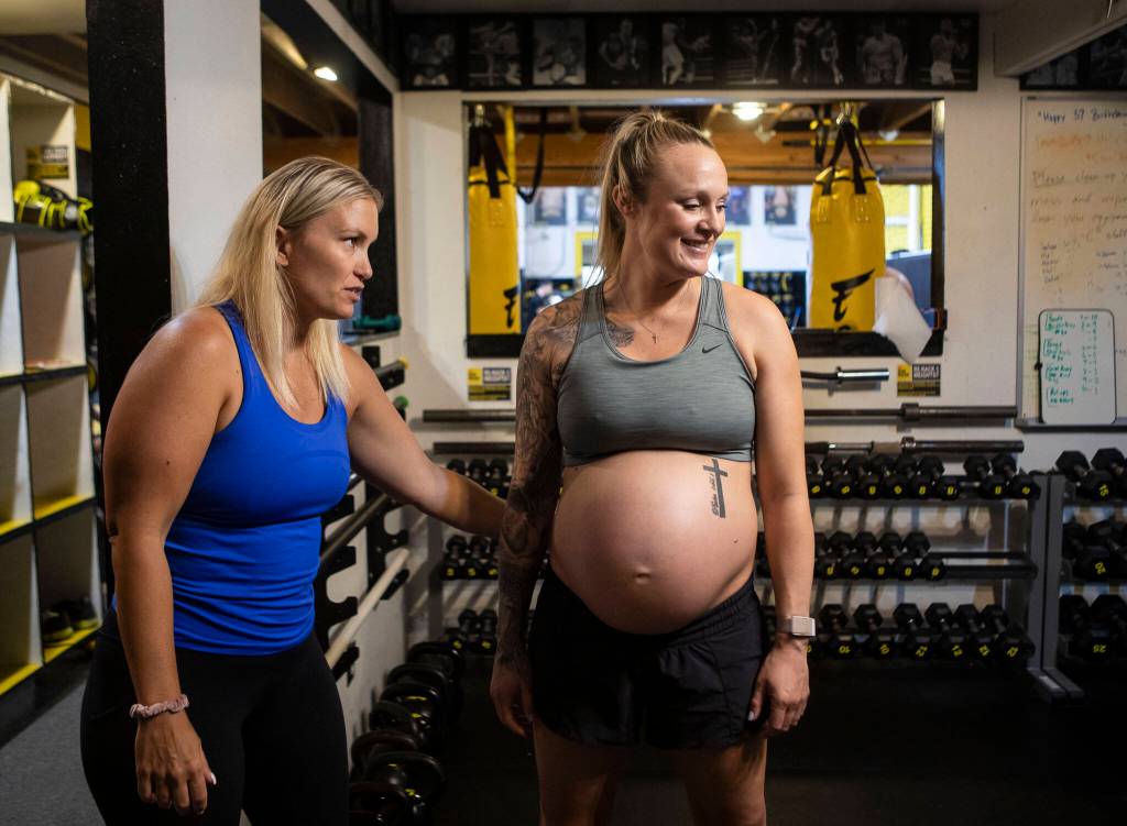 Brianna Battles, a strength and conditioning pregnancy and postpartum coach, talks Miranda Granger through one of her workouts while she is in town at Charlies Combat Club on Tuesday, Aug. 10, 2022, in Everett, Washington. (Olivia Vanni / The Herald)