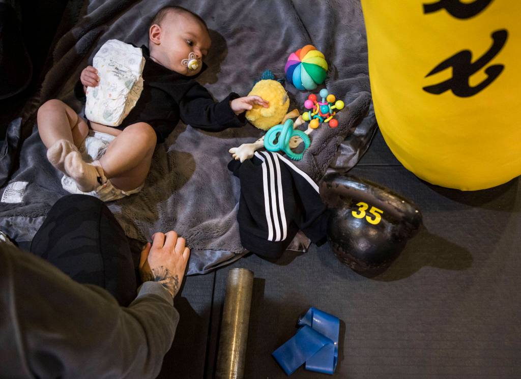 Austin holds onto a diaper and reaches for one of her toys while Miranda Granger gets ready to change her diaper at Charlies Combat Club on Monday, Feb. 28, 2022, in Everett, Washington. (Olivia Vanni / The Herald)