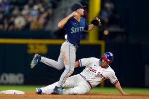 Texas Rangers' Corey Seager, right, slides into second base on the force out causing Seattle Mariners second baseman Adam Frazier (26) to hold the throw to first base during the 8th inning of a baseball game in Arlington, Texas, Saturday, Aug. 13, 2022. Rangers' Adolis Garcia was safe at first and the Rangers won 7-4. (AP Photo/LM Otero)